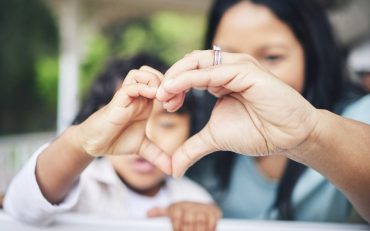 Mother, child and heart hands for love, care or compassion together in the outdoors. Mom and little